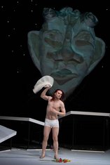 "Achill unter den Mädchen", KHP, Achill (Elmar Hauser) steht nur in Unterhose bekleidet vor einer großen Maske