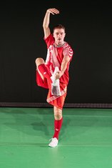 "Wir im Finale", Ein Fußballspieler in rotem Trikot macht eine Tanzpose auf einem Bein