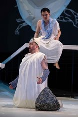 "Achill unter den Mädchen", GP, Phönix (Haozhou Hu) sitzt erhöht über dem am Boden knieenden, als Zyklop verkleideten Odysseus (Isaac Tolley)